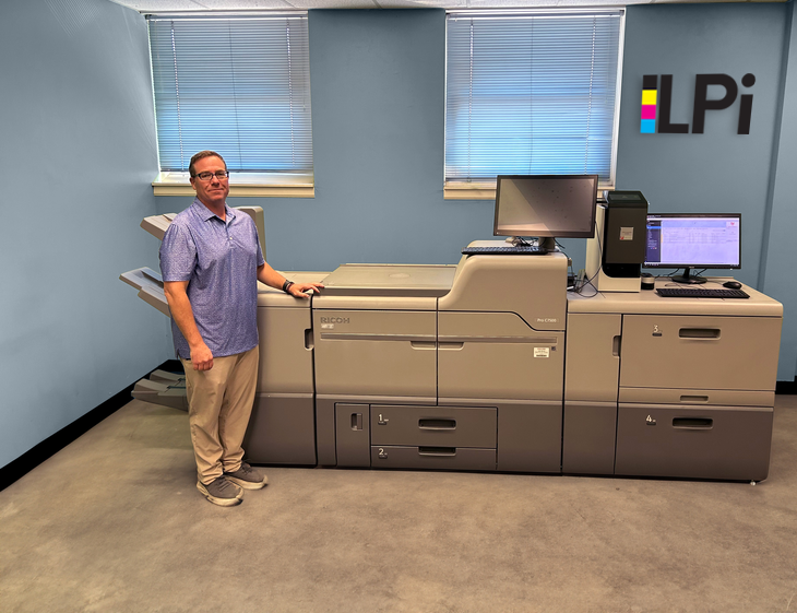 A man is standing in front of a large lpi machine