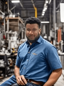 A man in a blue shirt is sitting in a chair in a factory.