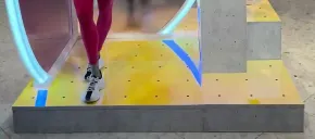 Person in pink leggings and white sneakers walking up yellow steps with blue accents.