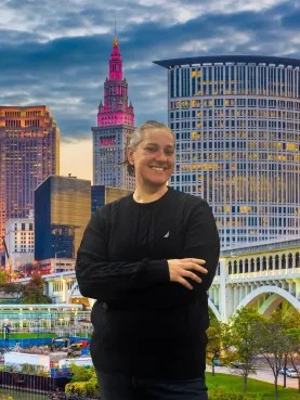 A woman stands in front of a city skyline with her arms crossed