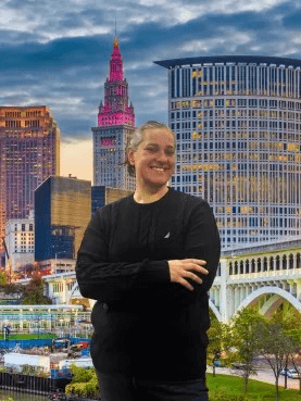 A woman in a black sweater stands in front of a city skyline