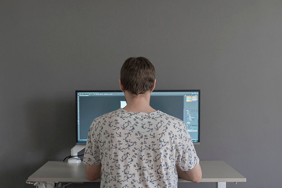 A man is sitting at a desk in front of a computer monitor.