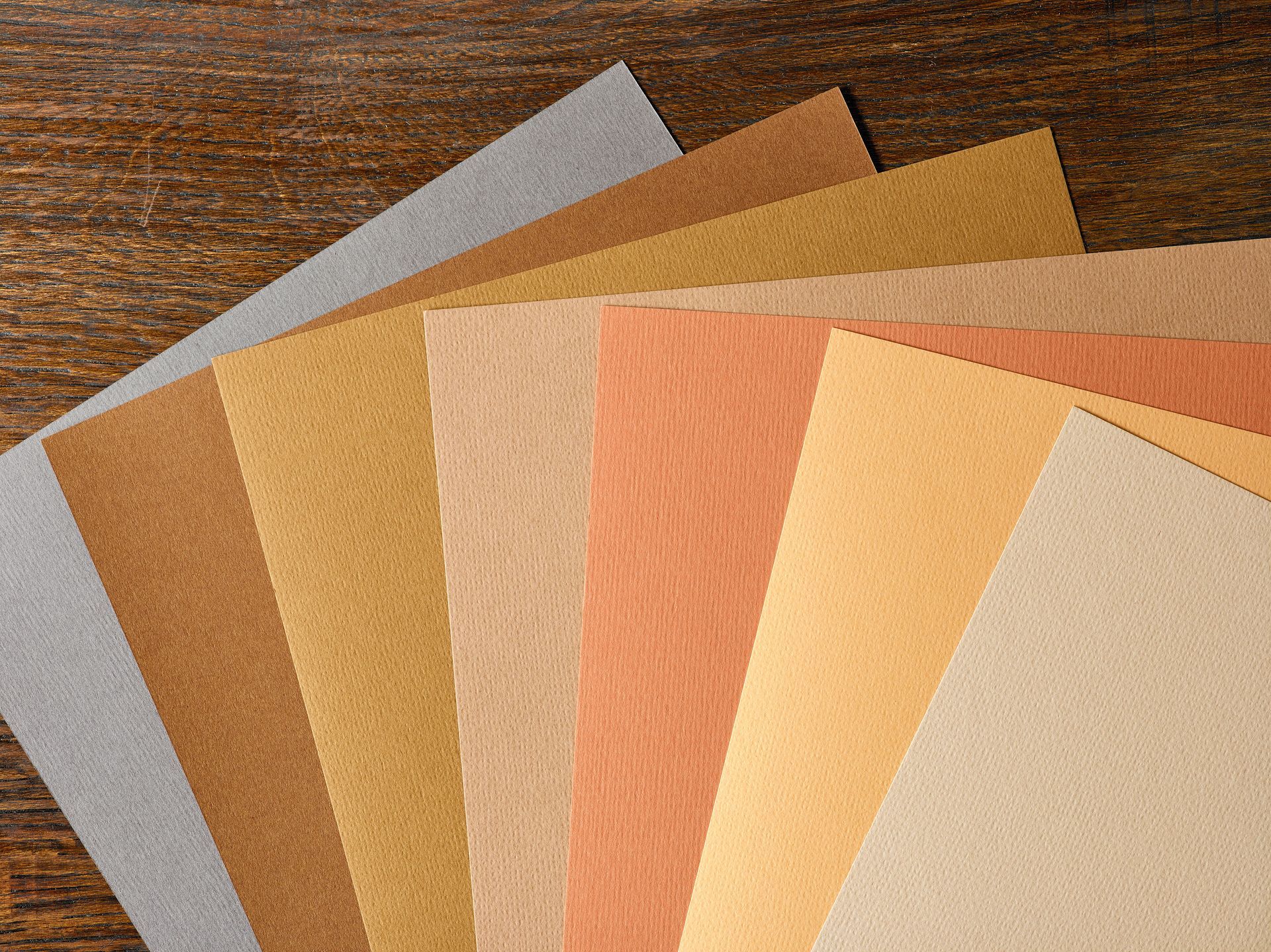 A bunch of different colored sheets of paper on a wooden table