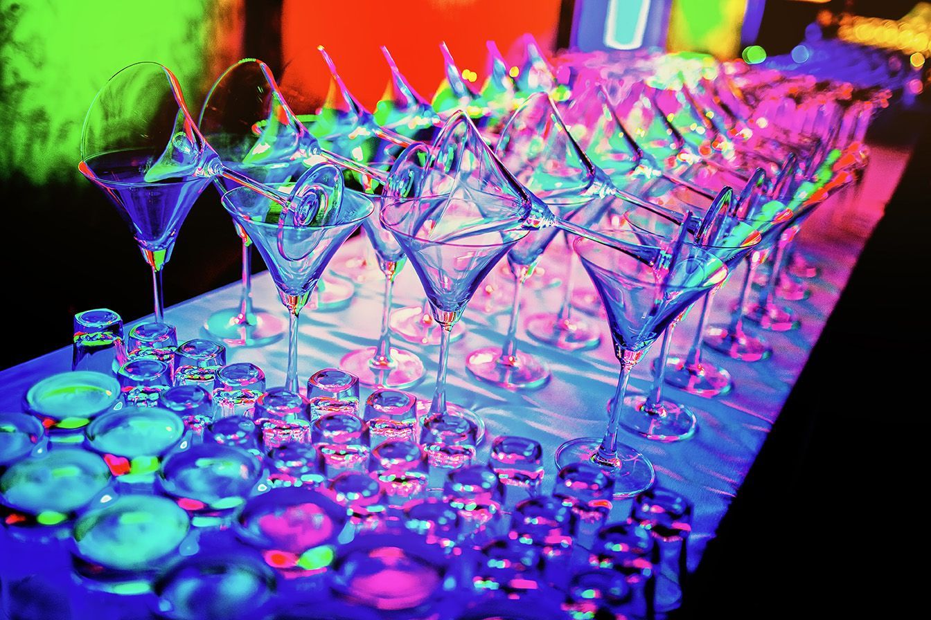 A table topped with a row of glow in the dark martini glasses.