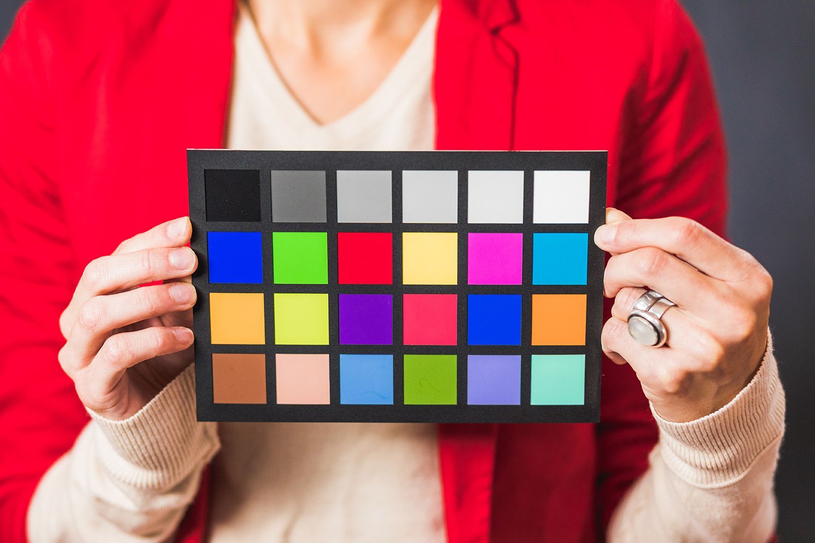 A woman in a red jacket is holding a color palette in her hands.