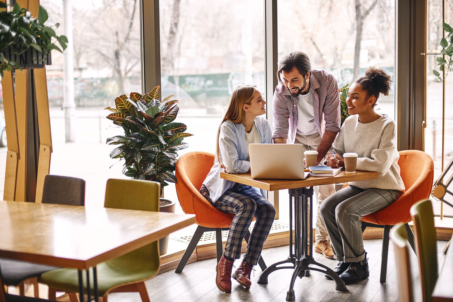 A group of people are sitting at a table looking at a laptop.