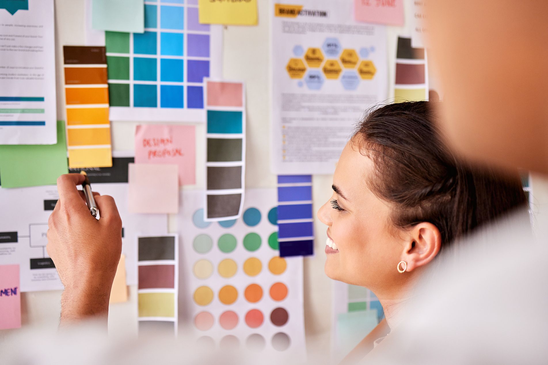 A woman is standing in front of a wall with sticky notes on it.