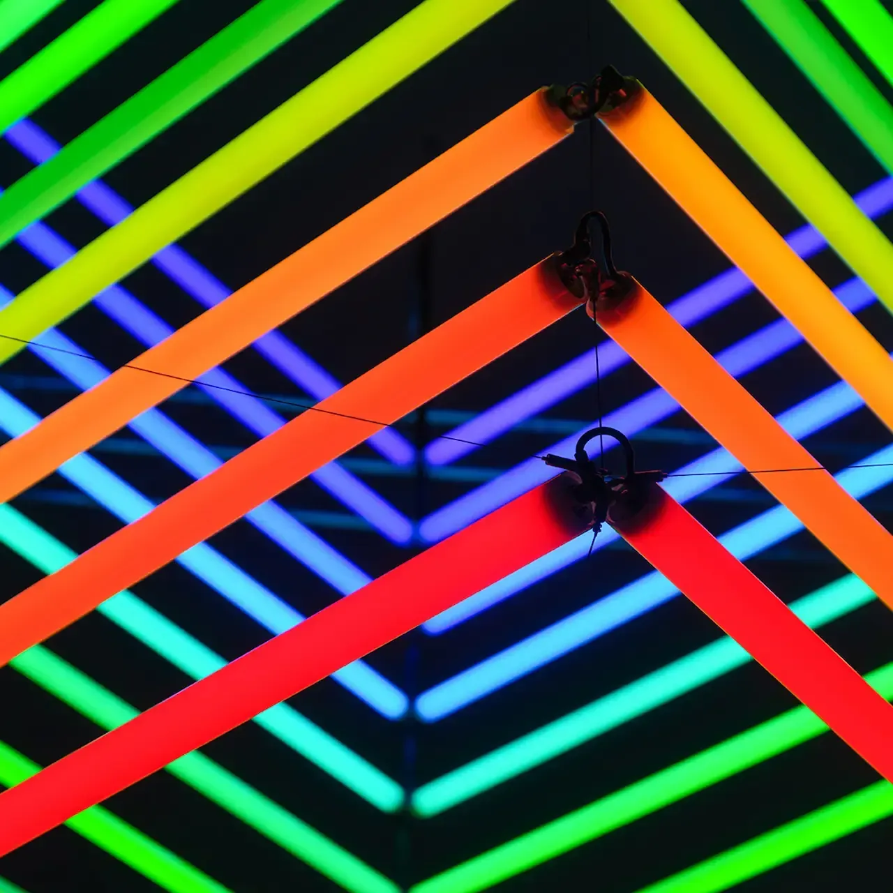 Colorful neon light installation with intersecting lines creating a geometric pattern.