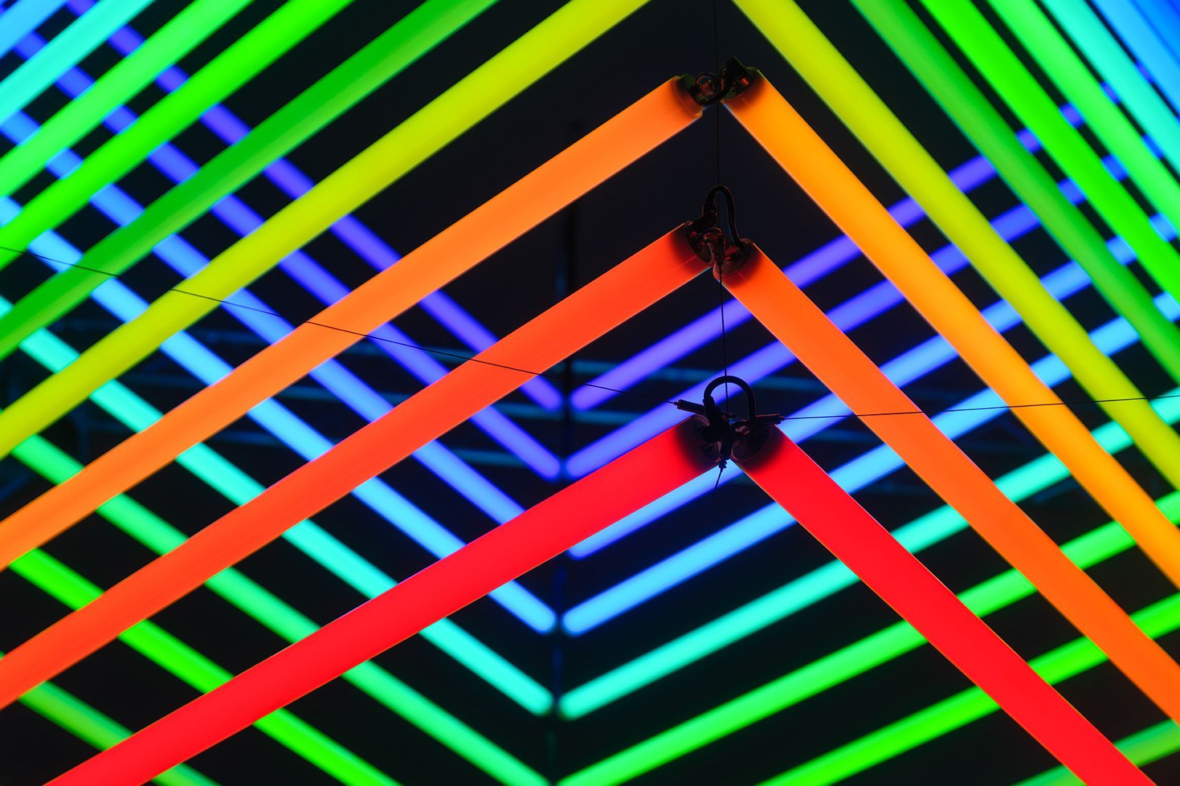 A close up of a ceiling with a rainbow of neon lights.