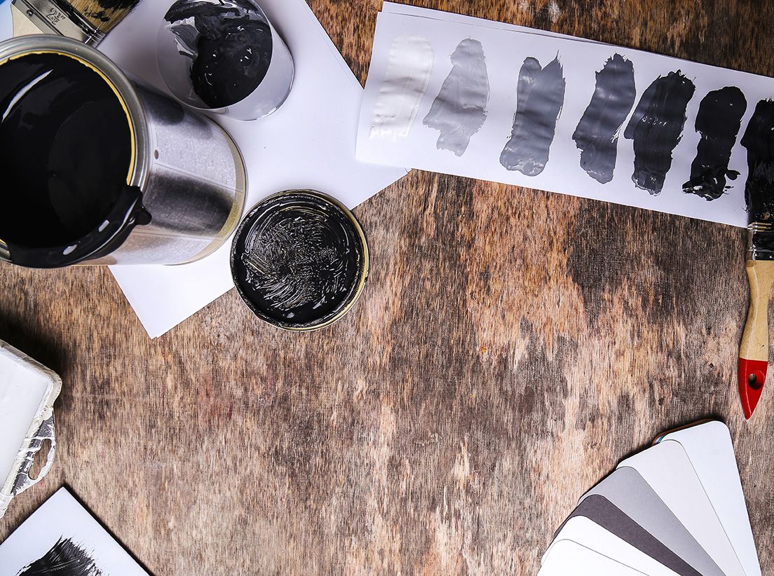 A wooden table with a bottle of black paint and a brush.