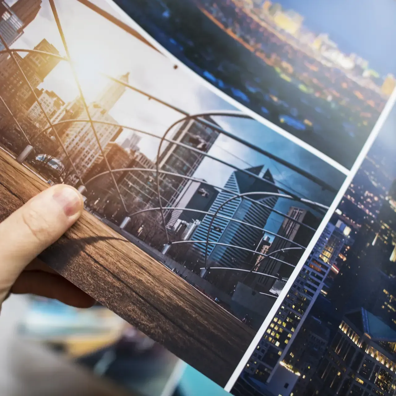 Hand holding stack of colorful prints featuring city skylines.