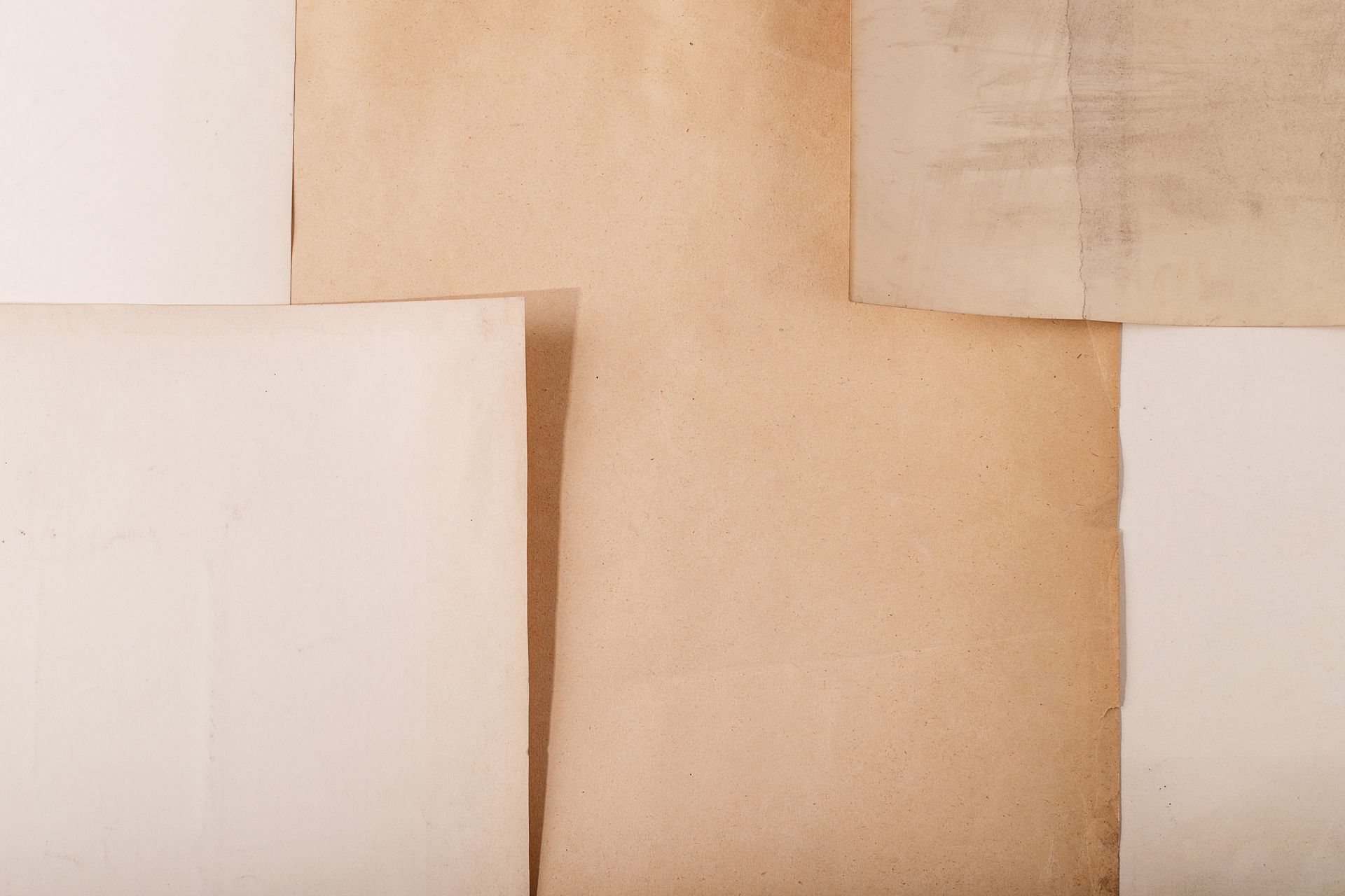 Torn pieces of various aged paper layered together, shades of beige and white.