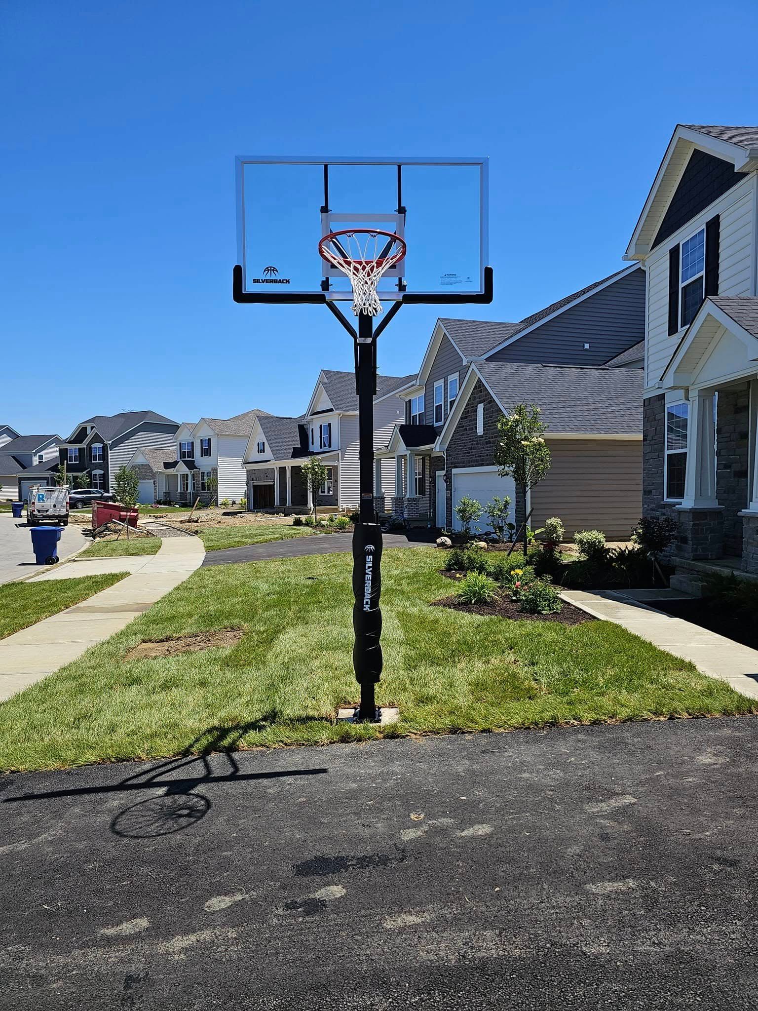 A basketball hoop is in the middle of a residential neighborhood.
