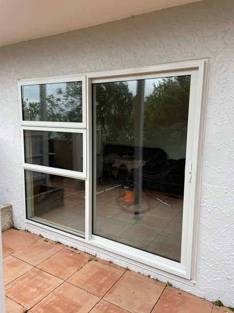 A White Sliding Glass Door is Sitting on a Tiled Patio — Lower Hutt, NZ — Complete Aluminium Maintenance Ltd