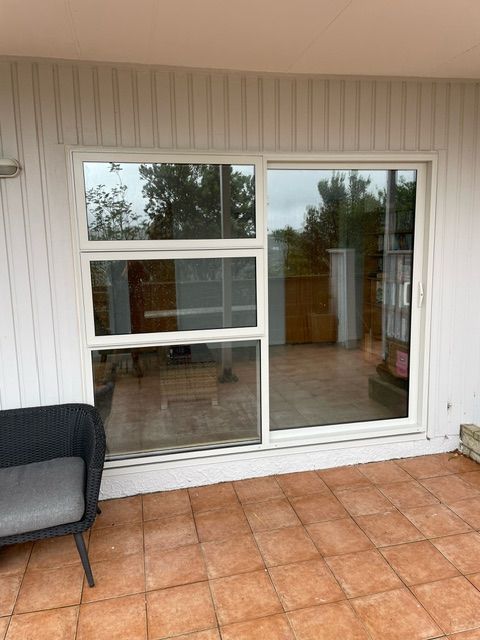 A Patio with a Sliding Glass Door and a Chair — Lower Hutt, NZ — Complete Aluminium Maintenance Ltd