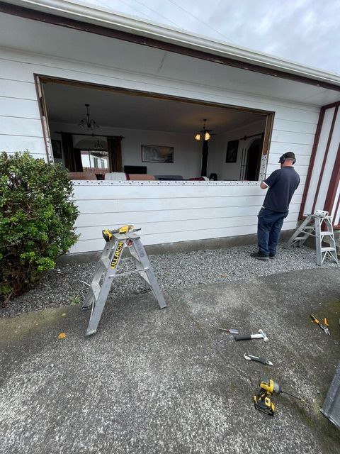 A Man is Standing on a Ladder in Front of a House — Lower Hutt, NZ — Complete Aluminium Maintenance Ltd