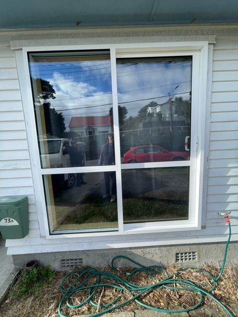 A White House with a Sliding Glass Door and a Hose in Front of it — Lower Hutt, NZ — Complete Aluminium Maintenance Ltd