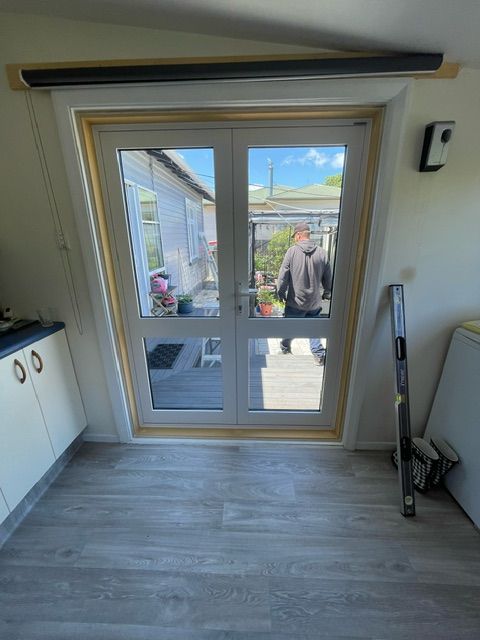 A Man is Standing in Front of a Sliding Glass Door in a Room — Lower Hutt, NZ — Complete Aluminium Maintenance Ltd