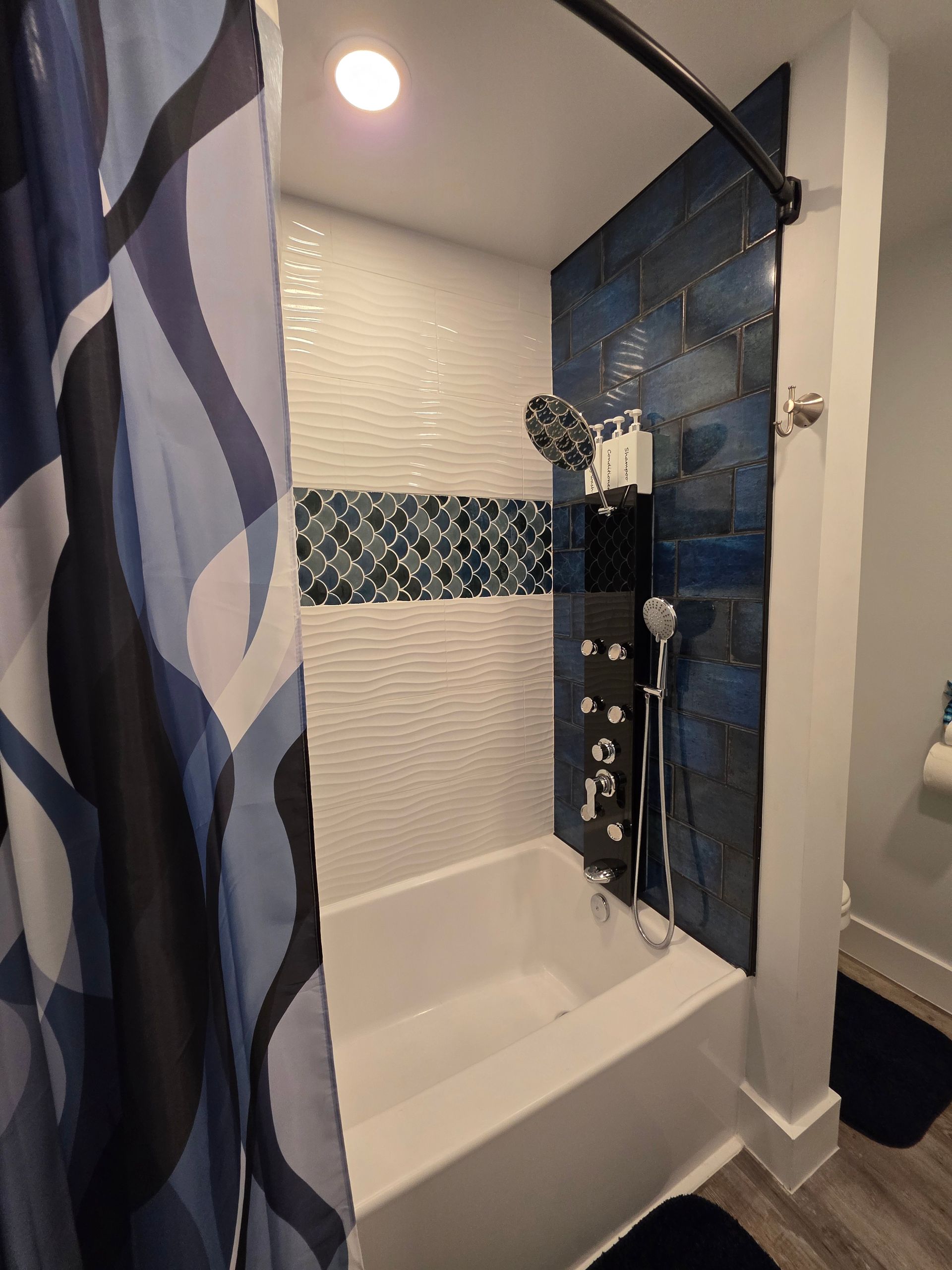 Bathroom with blue and white tile shower, tub, and shower curtain.