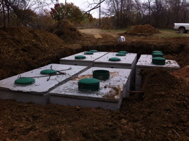 A row of septic tanks are sitting in the dirt.