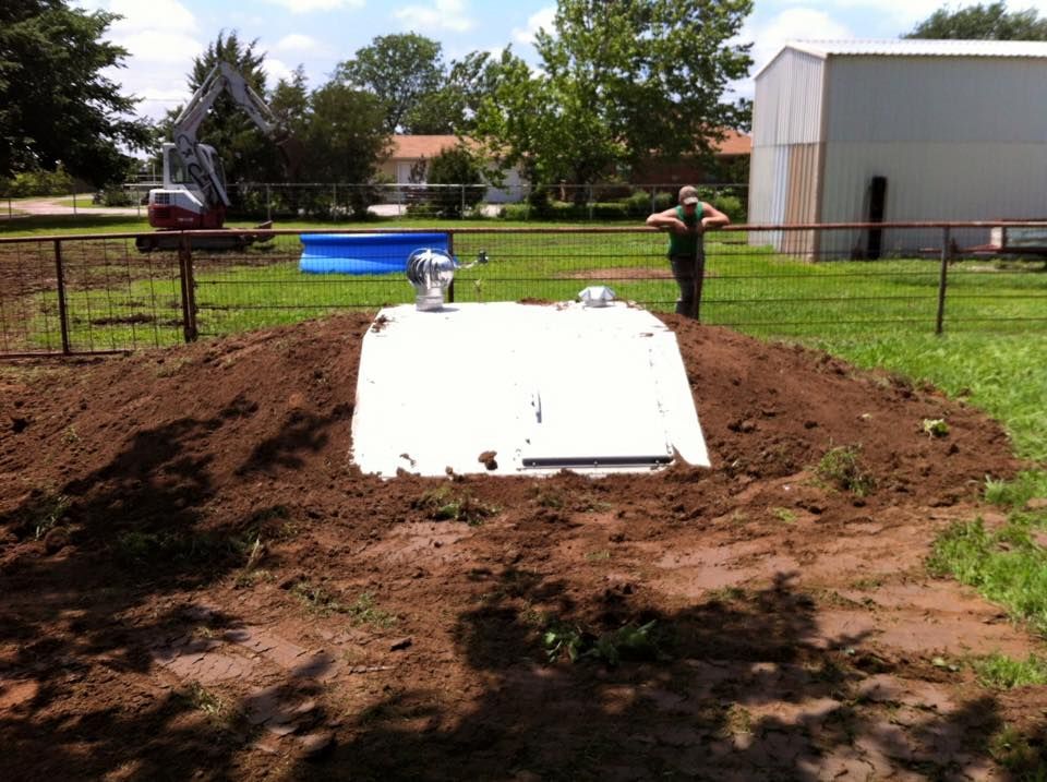 A man is standing in a field next to a white building