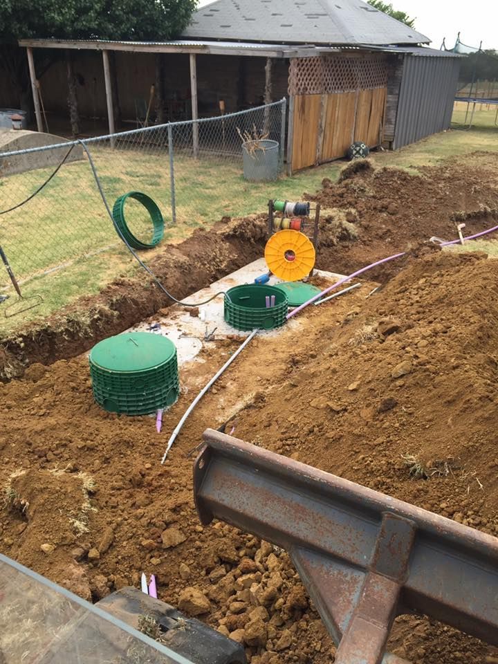A tractor is digging a hole in the dirt in front of a house.