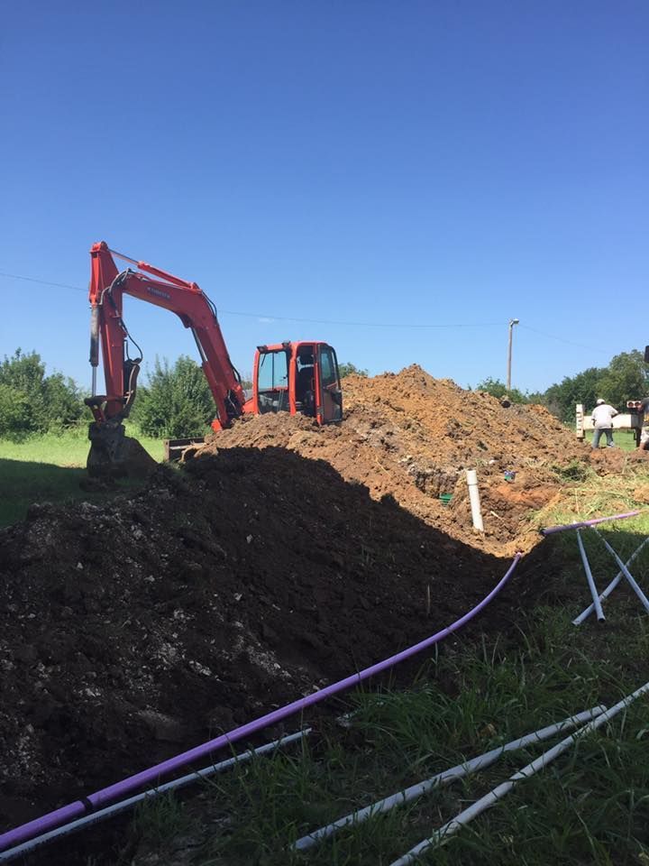 A red excavator is digging in a pile of dirt.