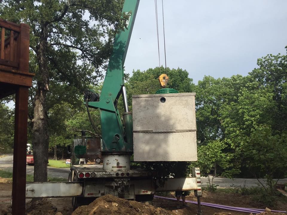 A green crane is lifting a large concrete box
