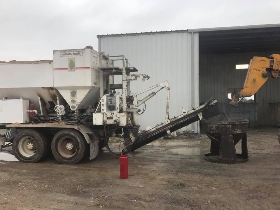 A concrete mixer truck is parked in front of a building.