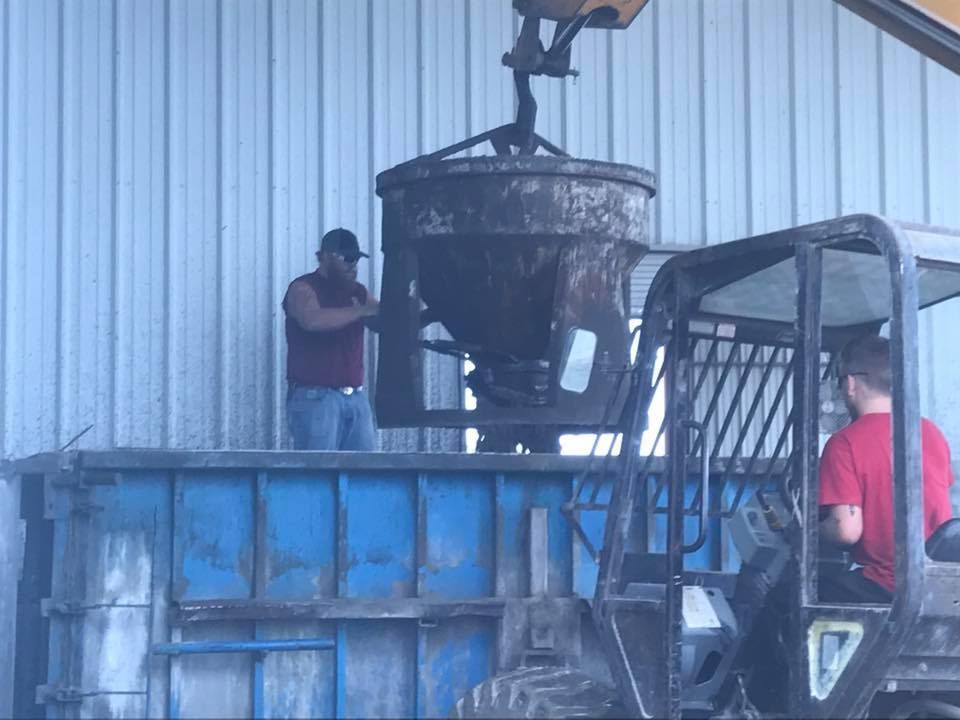 Two men are working on a machine in front of a building.