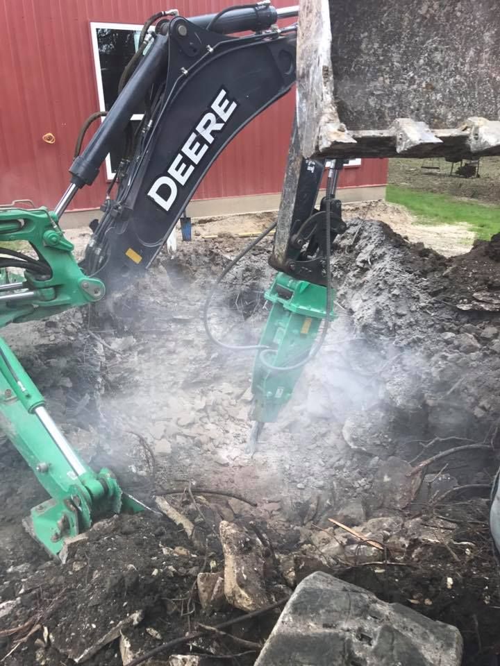 A deere excavator is digging a hole in the ground.