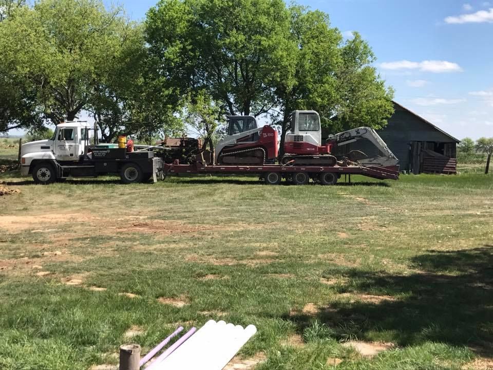 A truck is carrying a bulldozer on a trailer in a grassy field.