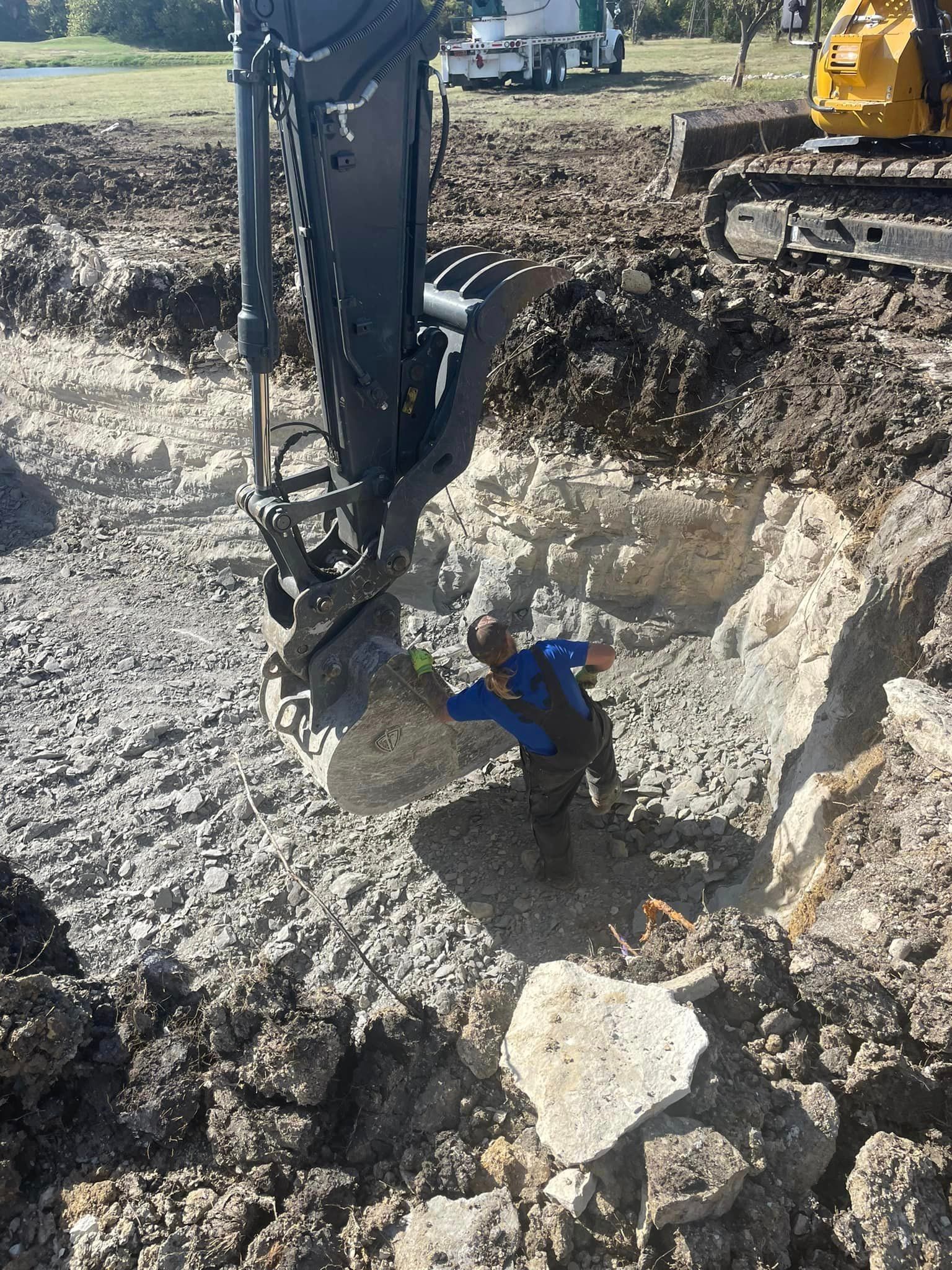 A man is standing in the dirt next to a bulldozer.