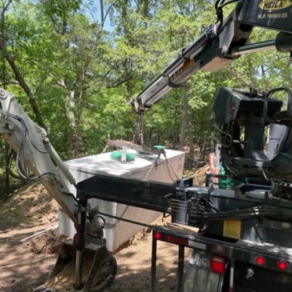A truck with a crane attached to it is digging a hole in the ground.