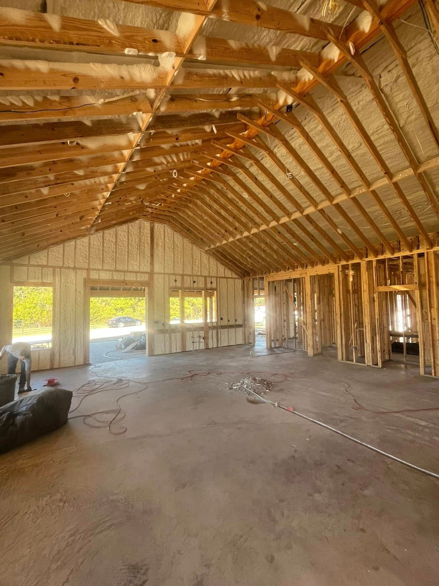 Interior of a building under construction, showing wooden framing and spray foam insulation.