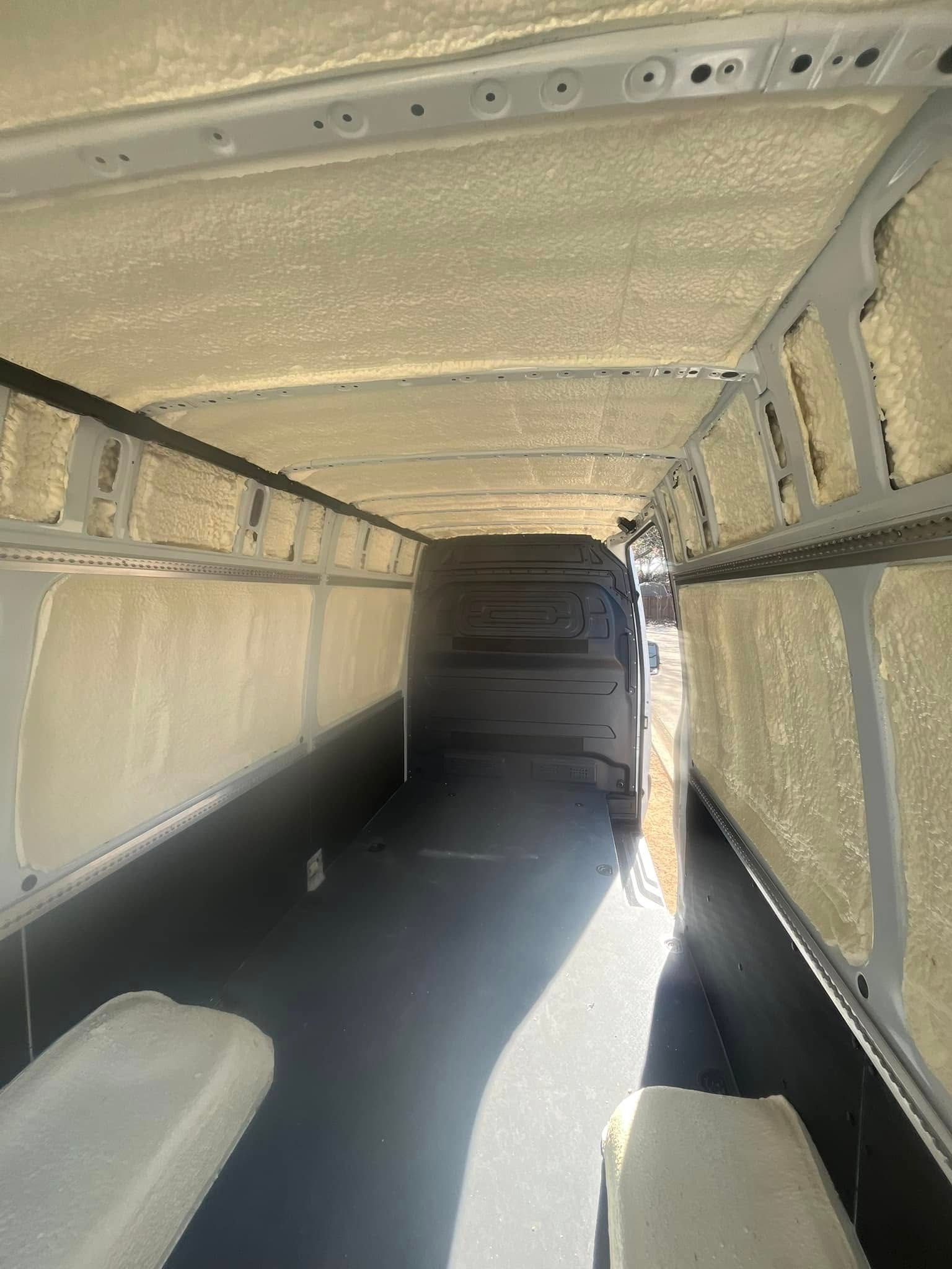 Interior of a van, insulated with light yellow material on walls and ceiling; black flooring.