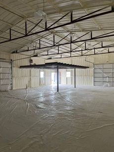 Interior of a building with concrete floor and spray foam insulation on walls and ceiling.