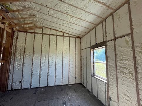 Interior of a room with spray foam insulation on walls and ceiling, window on right.
