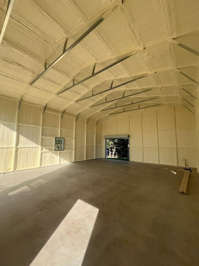 Interior of a building with spray foam insulation on the walls and ceiling, concrete floor.