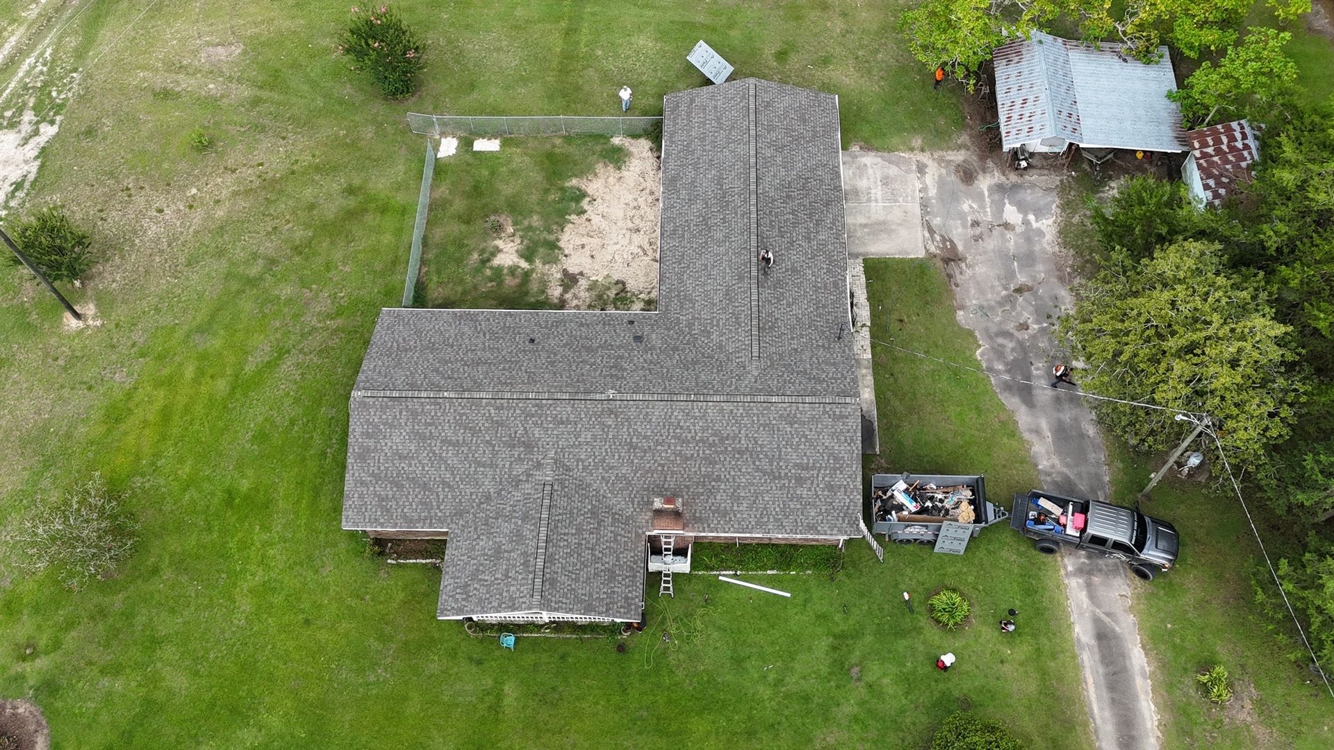Overhead view of a house with a gray roof, yard, and a truck parked nearby.