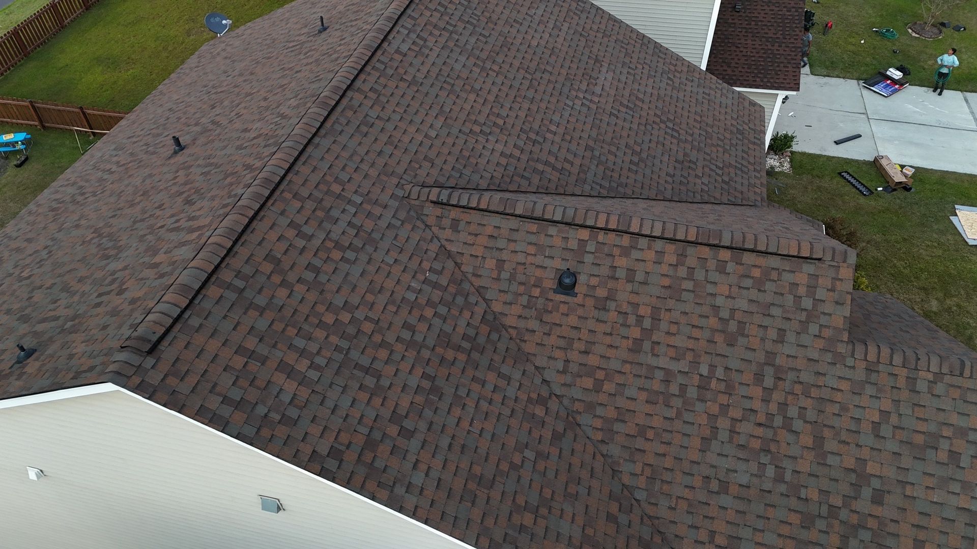 Dark brown shingle roof on a house with green grass surrounding it.