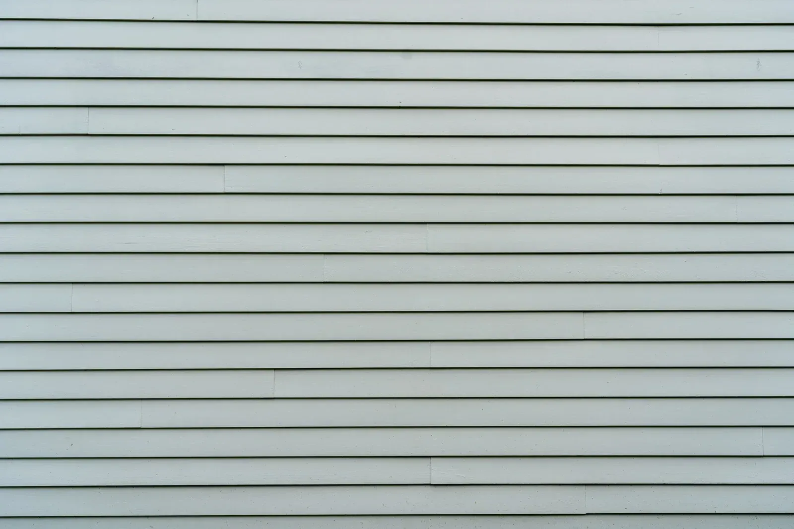 Horizontal, light blue siding on a wall.