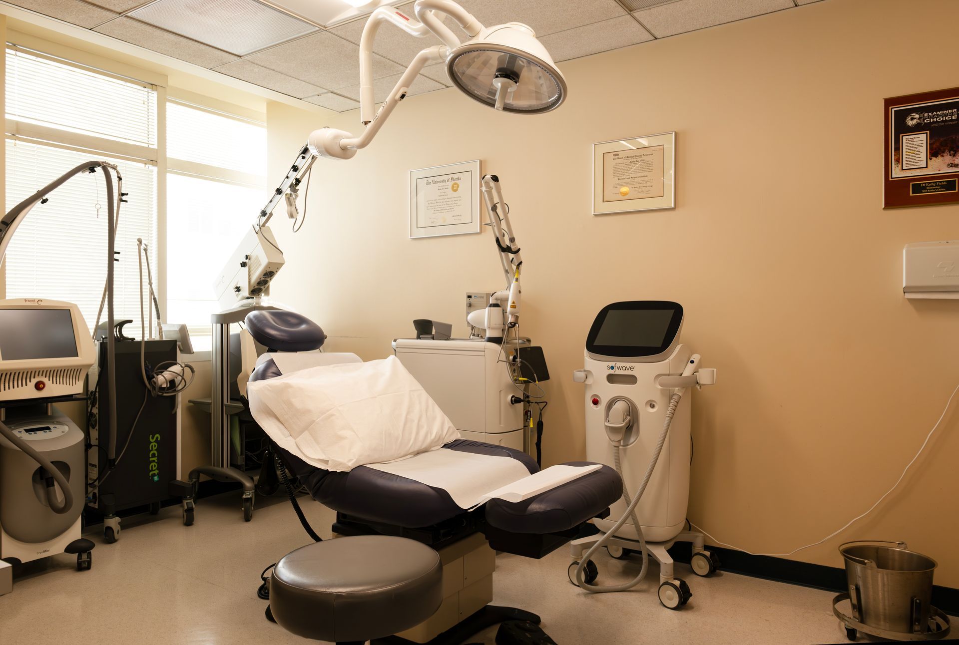 Medical office room with patient chair and laser treatment equipment.