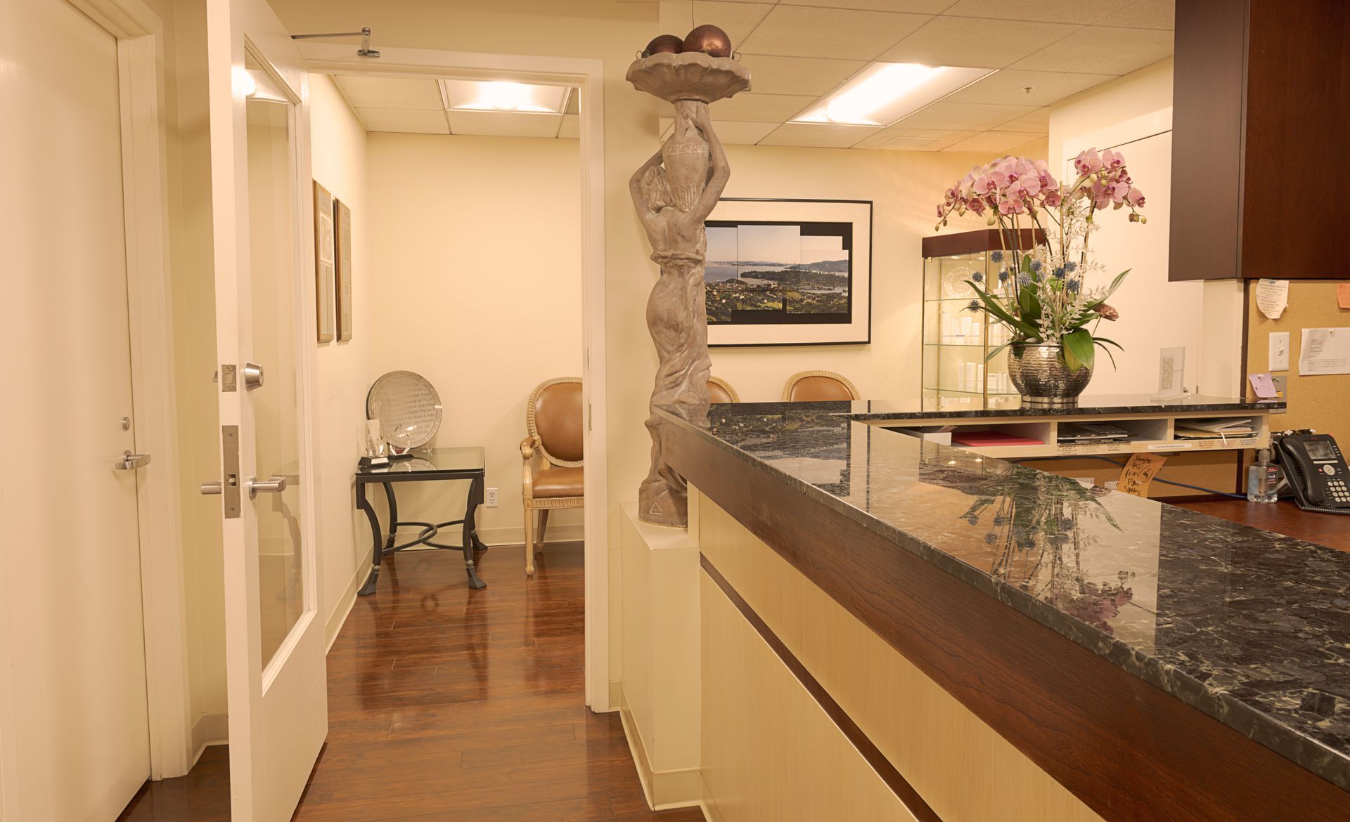 Reception area with a dark countertop and carved statue; a hallway with seating is visible.