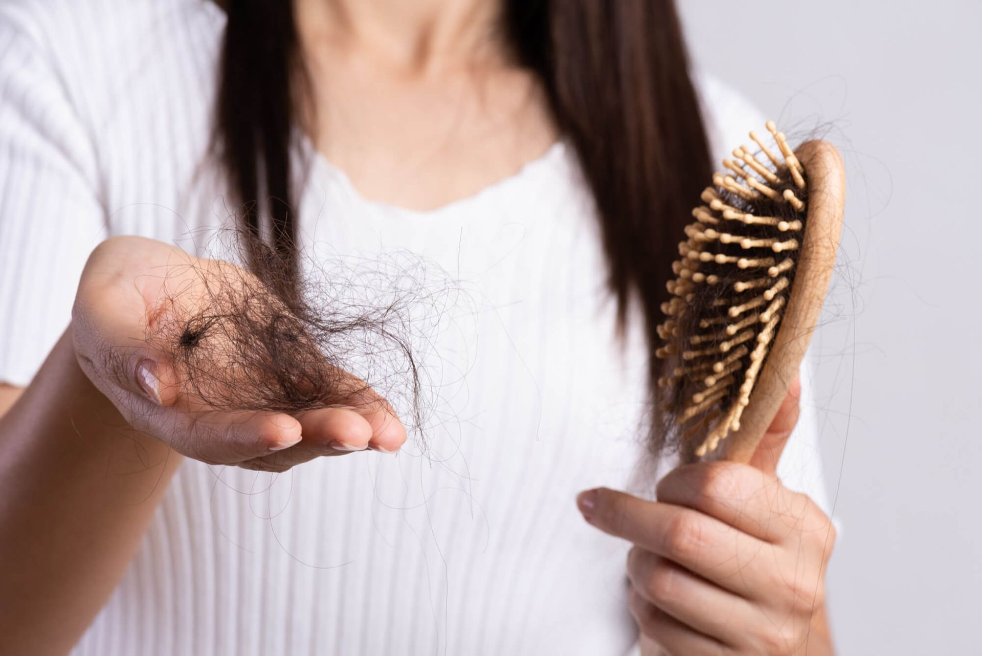 Woman show her brush with damaged long loss hair