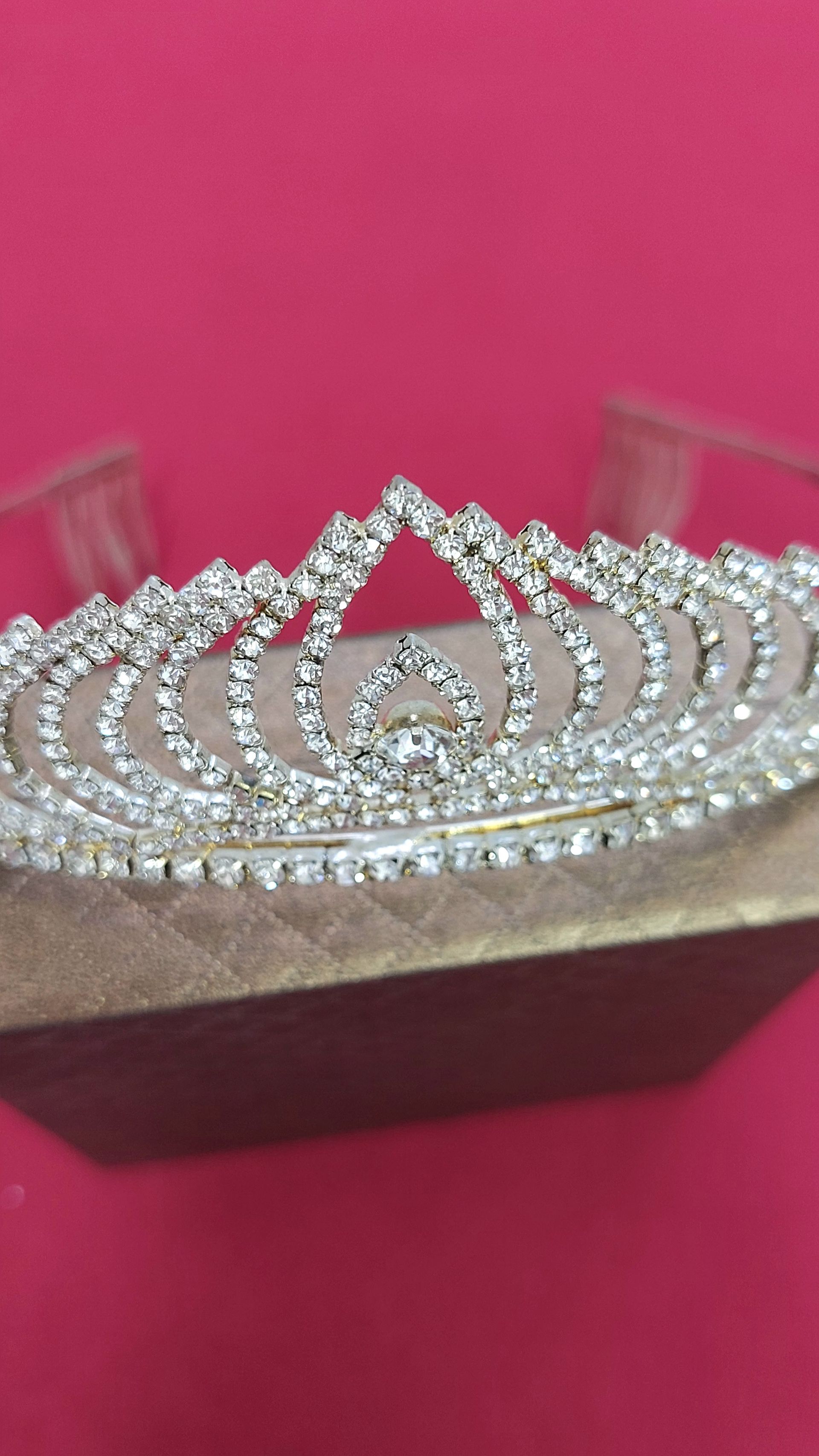 Tiara d'argento con strass su scatola marrone, su sfondo rosa.