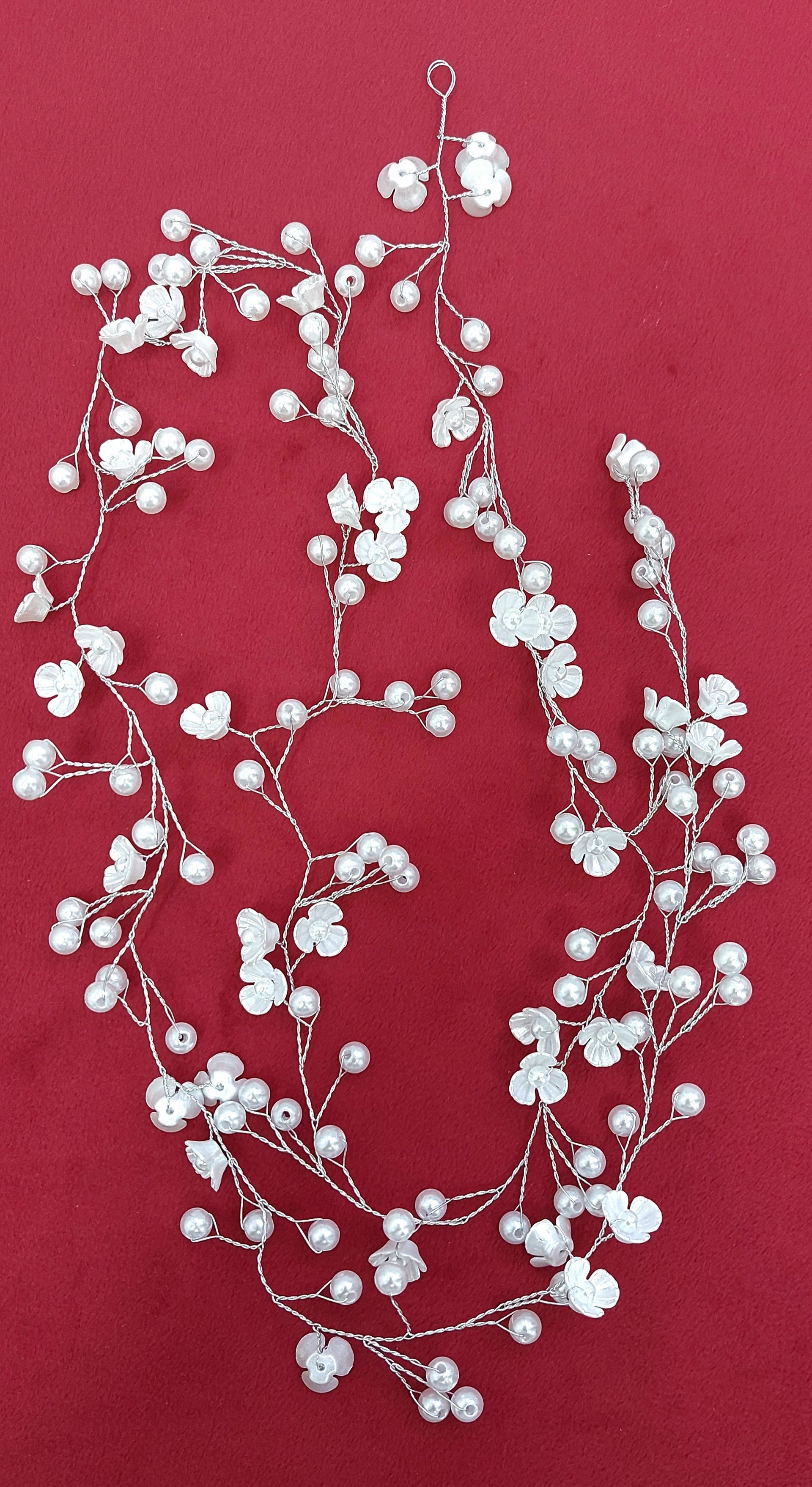 Rampicante con fiori bianchi e perle su sfondo rosso.