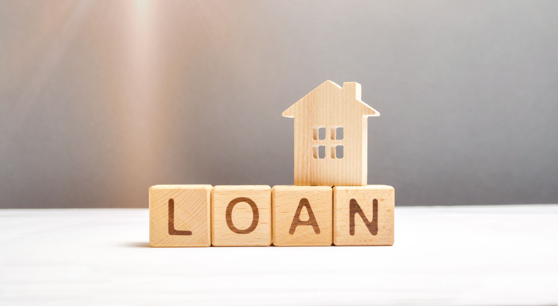 The word loan is written on wooden blocks with a house on top of them.