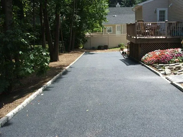 A driveway leading to a house with a deck.