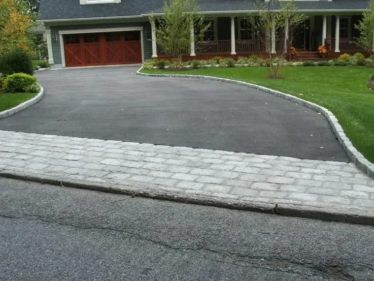 A driveway leading to a house with a wooden garage door.